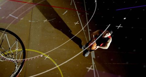 Overhead basketball player standing holding ball near hoop with dramatic lighting and shadow