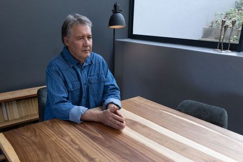 Senior Man Reflecting at Wooden Table in Modern Home Office