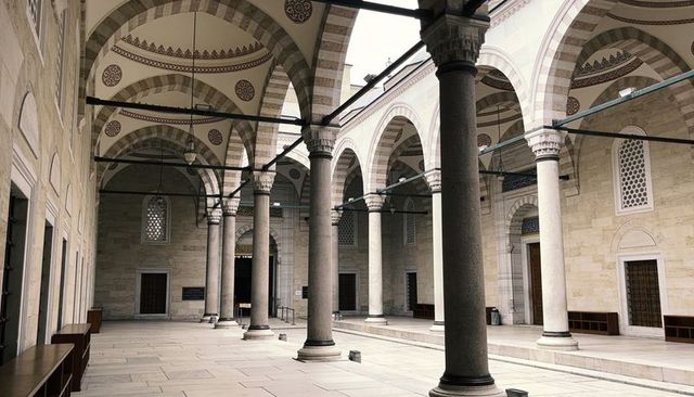 Historic ottoman mosque courtyard with marble columns, pointed arches and vaulted colonnade