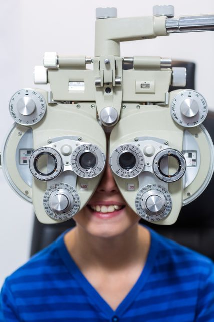 Young patient looking through phoropter during eye examination in ophthalmology clinic