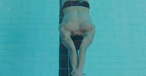 Competitive swimmer gliding underwater in streamlined push-off along black lane stripe