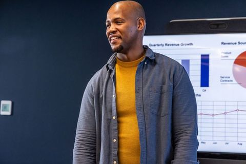 African american executive presenting revenue growth on screen in modern meeting room