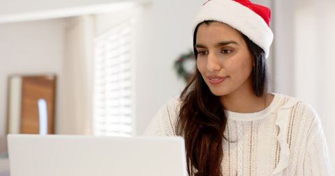 Woman in Santa Hat Using Laptop at Home for Holidays