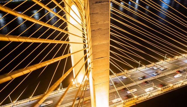 Highlighting Cable-Stayed Bridge Pylon and Golden Cables with Traffic Light Trails at Night