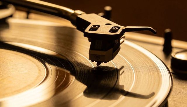Closeup spinning vinyl record with tonearm tracing groove on retro turntable