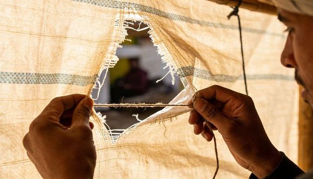 Repairing torn woven sack with twine under golden sunlight, vendor hands threading