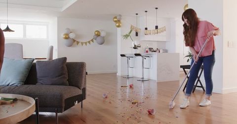 Young Woman Cleaning Living Room After Party Celebration