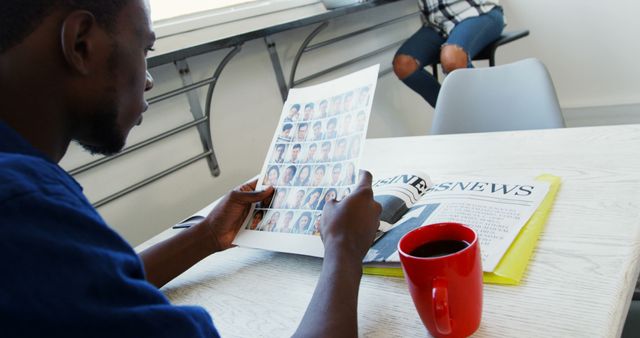 Man reading newspaper at table with coffee in red mug - Download Free Stock Images Pikwizard.com