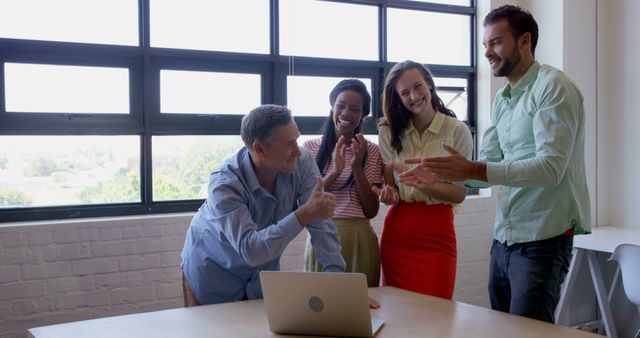 A diverse group of professionals celebrates a success at the office, with copy space. Their cheerful expressions and applause suggest a team victory or a job well done.