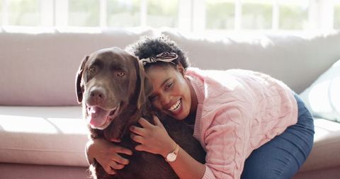 Joyful Woman Embracing Labrador on Sofa at Home