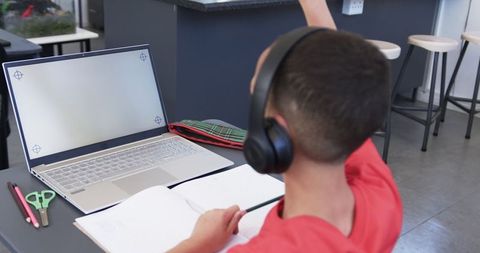 Focused student wearing headphones studying on laptop in classroom