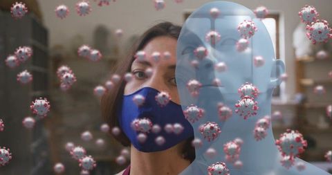 Woman wearing blue mask beside mannequin with floating coronavirus models in workshop