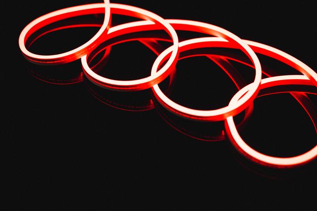 This image features an illuminated red neon spiral design against a black background. The glowing pattern creates a vibrant and futuristic look, making it ideal for use in modern design projects, advertisements, and digital art. The copy space allows for the addition of text or other elements, making it versatile for various creative applications.