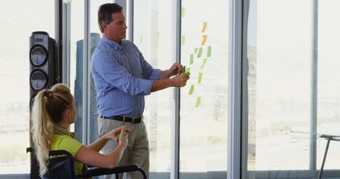 Colleagues Collaborating on Project with Sticky Notes in Bright Office