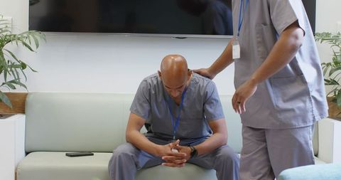 Male medical workers comforting stressed colleague in scrubs showing empathy teamwork