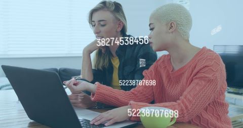 Diverse Female Couple Analyzing Data on Laptop with Digital Overlay