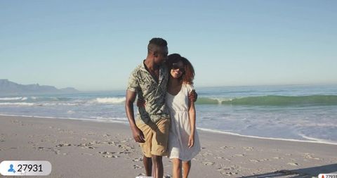 Joyful Couple Strolling on Ocean Beach During Sunny Day