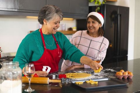 Smiling Mother and Daughter Making Holiday Cookies Together in Kitchen