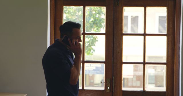 Businessman Standing by Window Talking on Phone - Download Free Stock Images Pikwizard.com