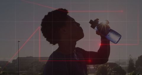 Afro american man drinking water against sunset silhouette