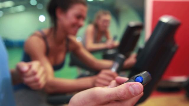 Trainer timing women working out on exercise bikes in gym. Perfect for fitness, training, and gym advertisements, health and wellness blogs, or workout inspiration.