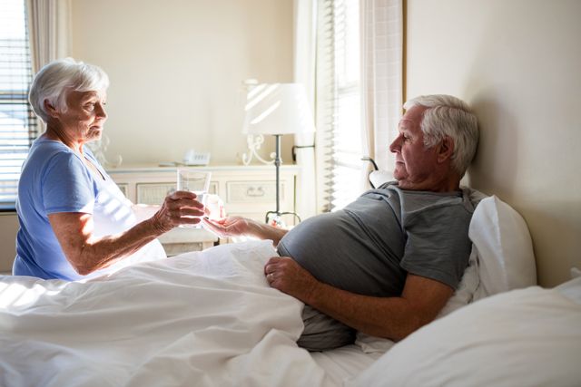Senior Woman Giving Medicine to Senior Man in Bedroom - Download Free Stock Photos Pikwizard.com