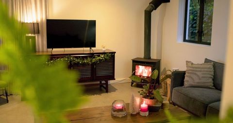 Cozy living room glowing with wood-burning stove, candlelit coffee table and greenery
