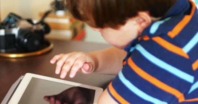 Young boy interacting with tablet. This can be used for promoting educational apps, showcasing home learning, addressing children's use of technology, or demonstrating modern teaching methods.