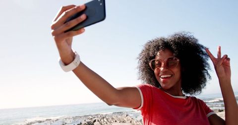 Joyful Woman Taking Selfie on Sunny Beach with Smartphone