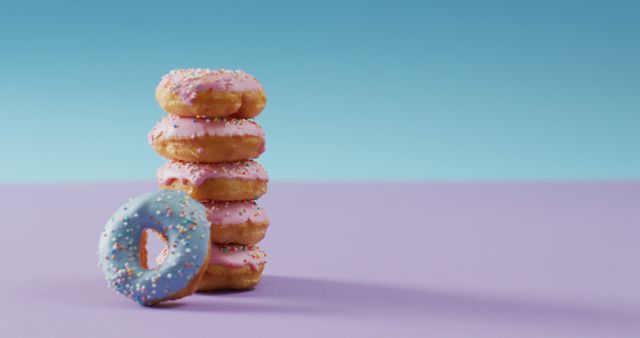 This image features a stack of pink frosted donuts with sprinkles beside a single blue frosted donut, all placed on a purple surface against a blue background. Perfect for use in marketing materials for bakeries, dessert blogs, or social media posts promoting sweet treats. It conveys a sense of indulgence and vibrant, eye-catching appeal.