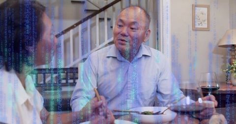Couple sharing dinner and conversation with blue digital code overlay at home