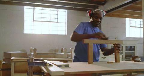 Artisan sanding wood frame in sunlit workshop