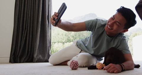 Man taking selfie with dog playfully indoors