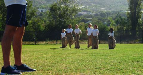 Diverse children competing in sack race at school sports day