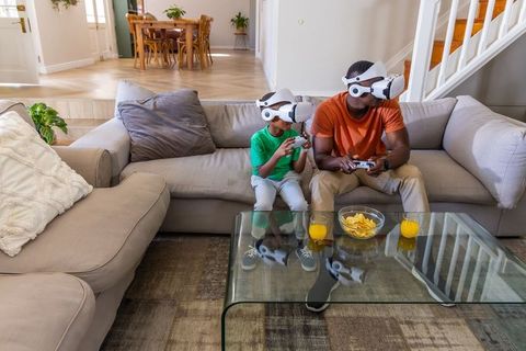 African American father and son enjoying virtual reality gaming in modern living room