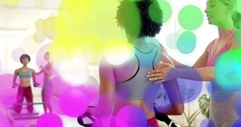 Instructor adjusting posture during indoor cycling class in bright studio