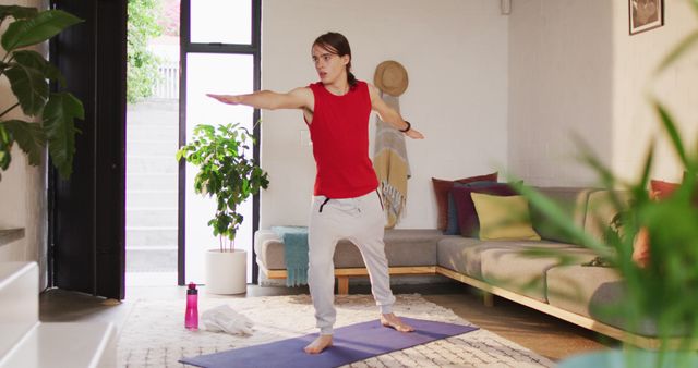 Young woman practicing yoga pose on mat in cozy living room. Ideal for content related to fitness routines, home workout inspirations, healthy lifestyle, mindfulness practices, and indoor exercise tips.