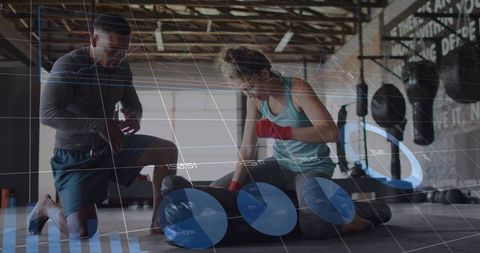 Kneeling trainers tending boxer with red hand wraps and ar performance overlays in gym