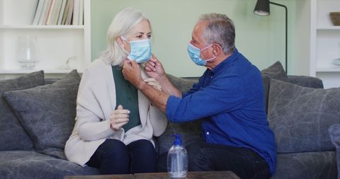 Senior Couple Adjusting Face Masks in Living Room Amid COVID-19