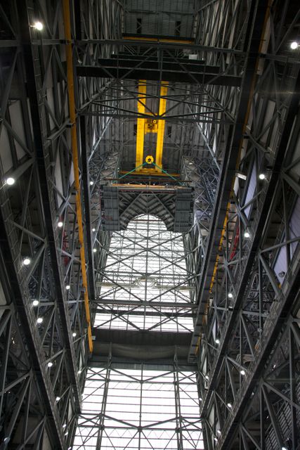 Crane lifts part of the work platforms high above the floor in NASA's Vehicle Assembly Building at Kennedy Space Center. The work platform section is prepared for installation on the south side of High Bay 3, 246 feet above the floor. Intended for Exploration Mission 1, this platform will aid in accessing the new SLS rocket and Orion spacecraft, integral to Mars exploration efforts. Perfect visual showcase for discussions on aerospace engineering, advanced construction techniques, and space mission preparations.