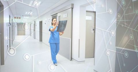 Nurse examining x-ray film in modern hospital corridor