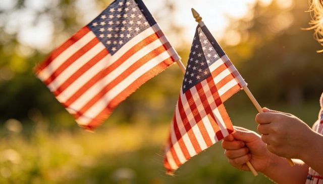 Child holding small american flags during golden hour in park