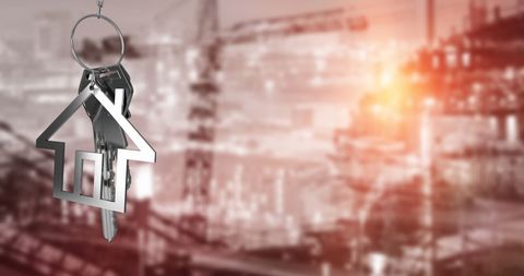 Silver house key with cityscape background and sunlight reflections