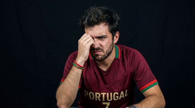 Portugal fan wearing no 7 jersey leaning pinching nose showing frustration and disbelief