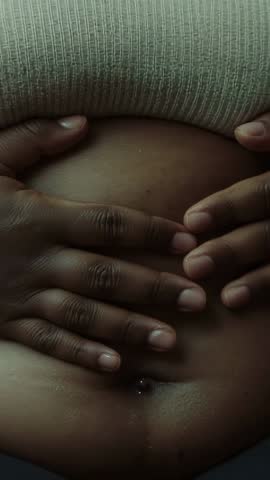 Placing hands on belly close-up vertical video showing navel piercing and ribbed top