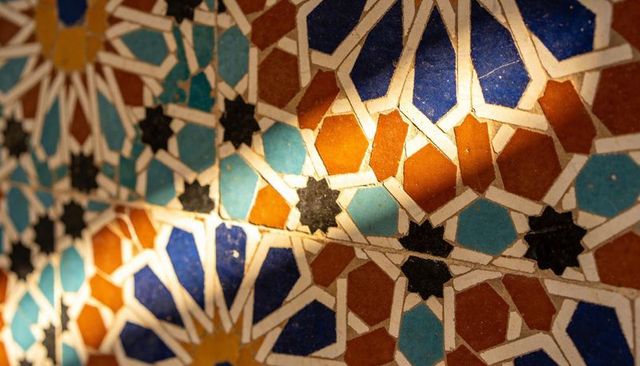 Sunlit islamic geometric mosaic wall featuring blue, turquoise and orange ceramic stars