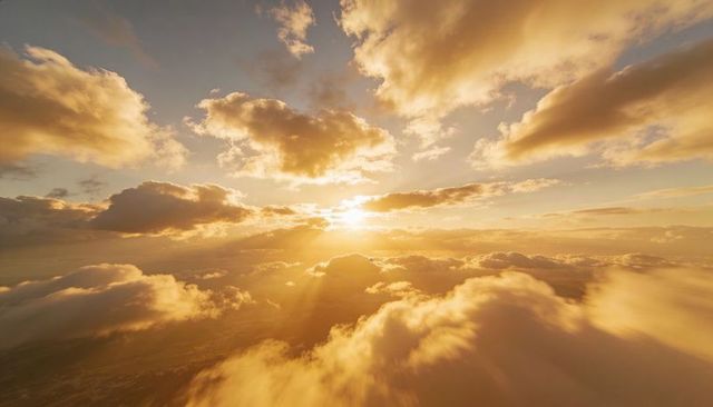 Golden sunrise above cumulus clouds casting dramatic sun rays across sky