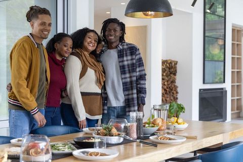 Multiracial friends celebrating around dining table in modern open-plan home interior