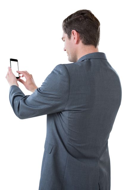 Businessman in formal suit using smartphone, ideal for illustrating corporate communication, technology use in business, or modern professional lifestyle. Suitable for business presentations, websites, and marketing materials.