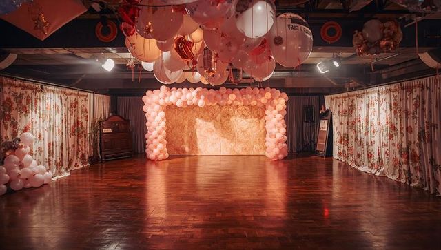 Pink Balloon Arch Framing Golden Backdrop Over Polished Wooden Dance Floor for Reception